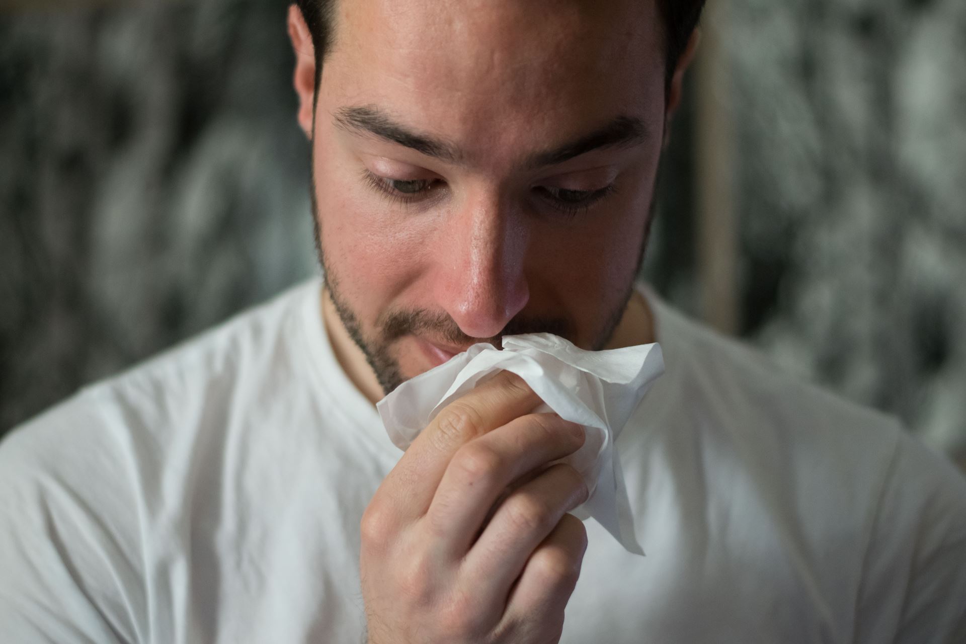 a man blowing his nose with a tissue